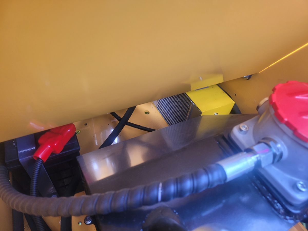 <p>Pod podlahou obsluhy je <strong>chladič hydraulického oleje</strong> s elektrickým <strong>ventilátorem</strong>. Ventilátor se zapíná dle teploty oleje mechanicky, z místa obsluhy.</p>
<p>V tomto prostoru je umístěn i <strong>akumulátor</strong>.</p>